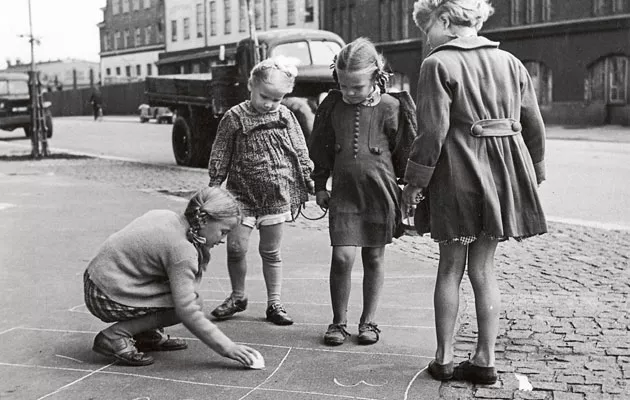 Lapset leikkii kadulla 1940-luvun kaupungissa.