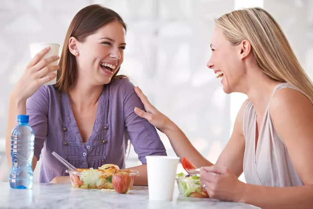 Kaksi naista syömässä eväitä työpaikalla