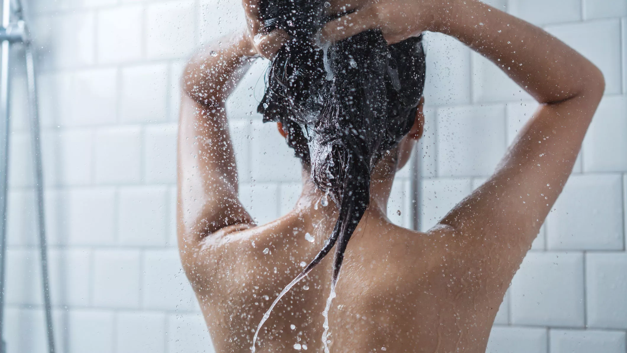 Nainen pesee hiuksiaan suihkussa