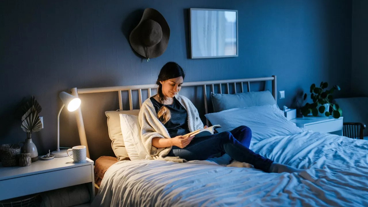 nainen lukee kirjaa sängyssä