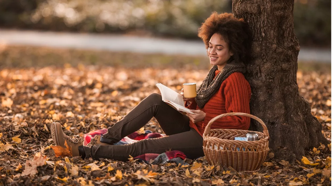 nainen lukee syksyllä kirjaa