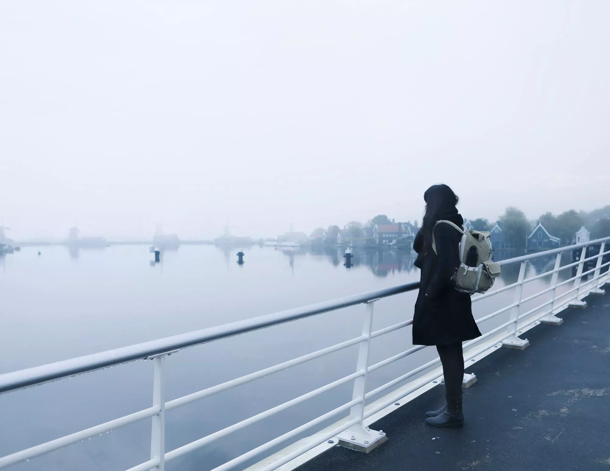 Ilmastoahdistus: Nainen seisoo sillalla ja katsoo sumuista maisemaa