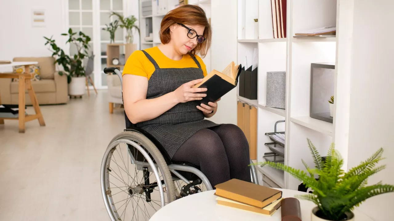 nainen lukee kirjaa pyörätuolissa