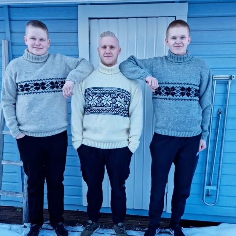 Kolme miestä seisoo ulkona villapaidat päällään.