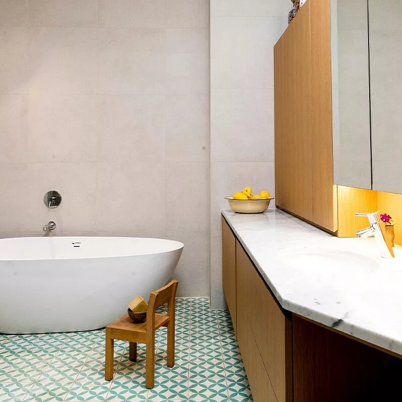 Sementtipuristeiset Portugalista hankitut laatat tuovat tähän kylpyhuoneeseen ilmettä. Pesukone ja pyykkihuolto piiloutuvat kaappien sisään.