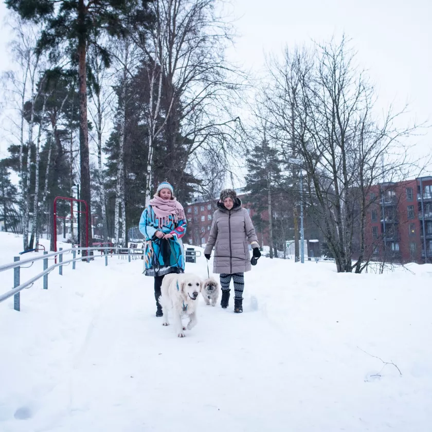 Nelly Kärkkäinen ja Gitta Oksanen ulkona talvisessa maisemassa koiriensa kanssa.