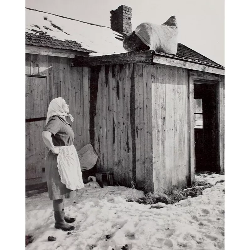 Vuonna 1963 otetussa kuvassa emäntä on asettanut kiirastorstaina säkillisen heiniä navetan katolle.