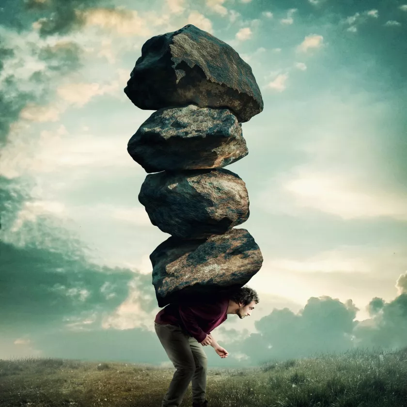 Mies kantaa selkänsä päällä kiviä