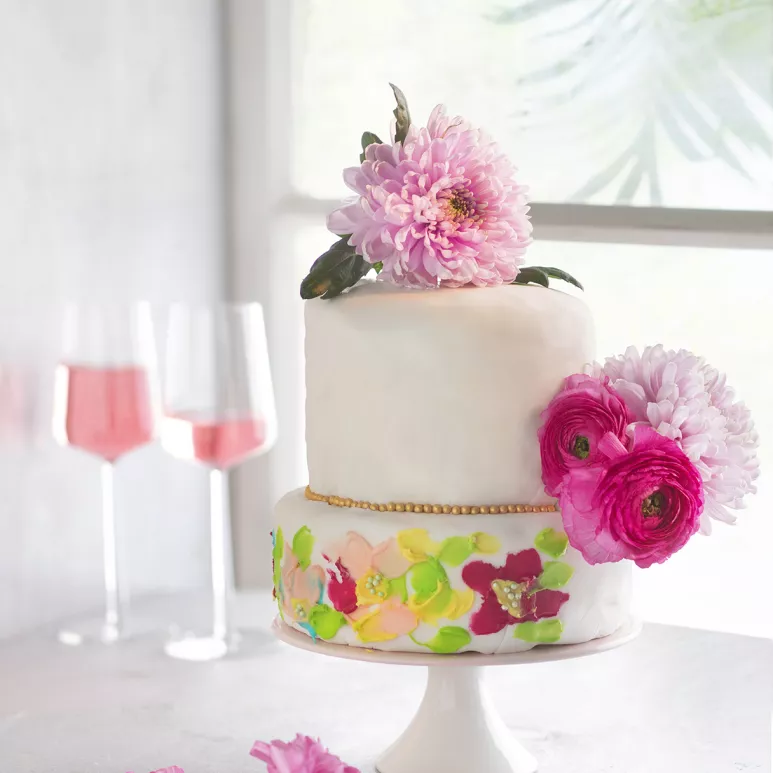 Gluteeniton vadelma-ruusukakku on koristeltu kukilla. Kukkia on maalattu kakun pintaan sekä työnnetty koristeeksi kakun kerrosten väliin. 