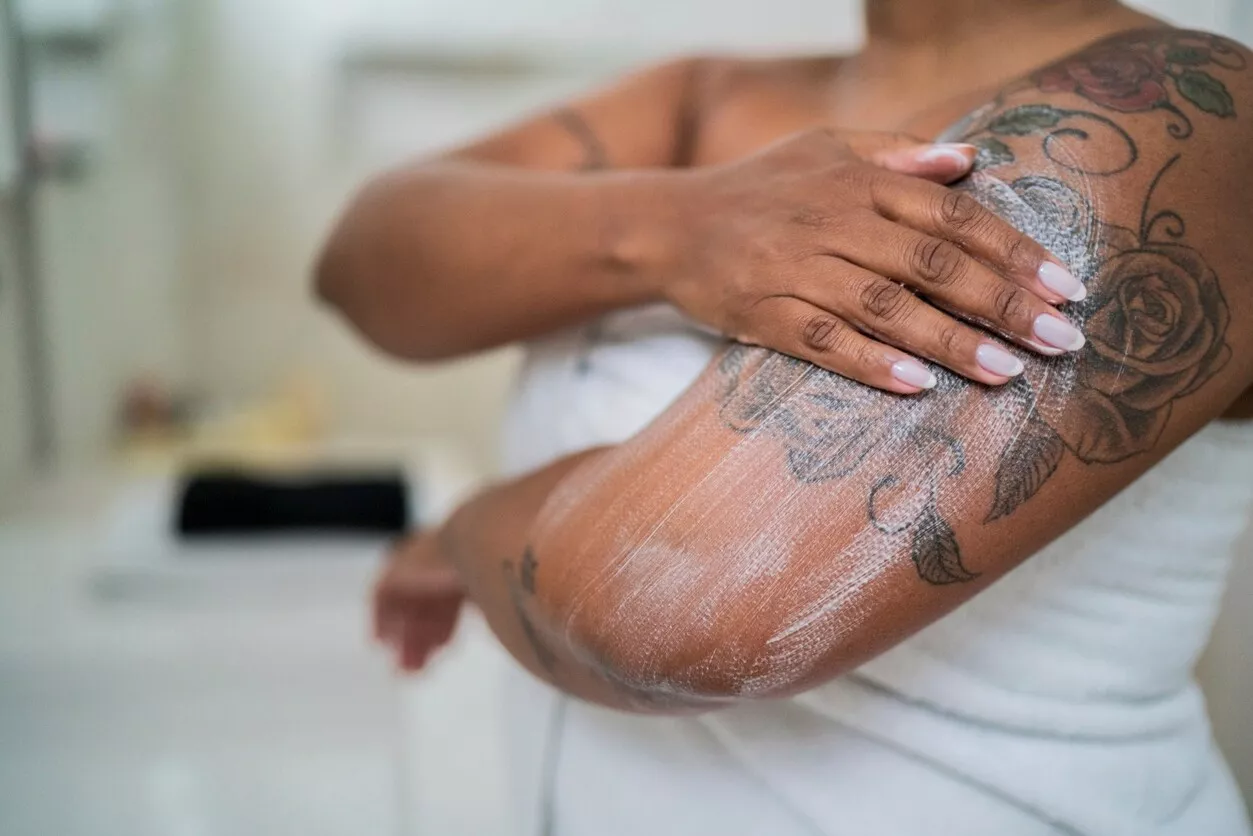 nainen levittää rasva käsivarren iholle