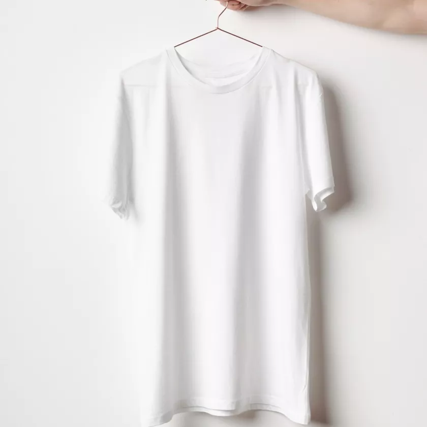 Tahranton valkoinen paita henkarissa, jota käsi pitelee