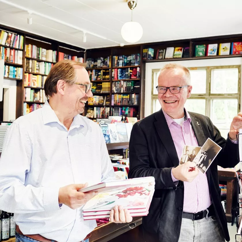 Mikko Vartiainen ja Pasi Vainio keskustelevat iloisina kirjakauppansa myymälässä. 