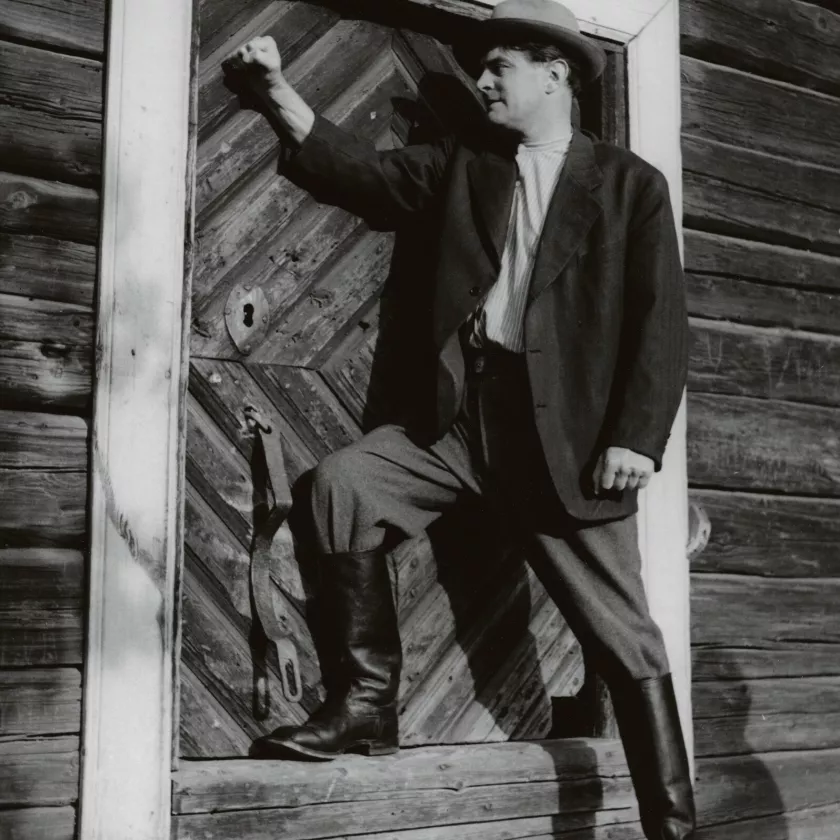 Turhaan paukuttaa isäntärenki Kalevi (Tauno Palo) aitan komeaa ovea, sillä Hilja ei sitä hänelle aukaise.  Kuva elokuvasta Hilja maitotyttö (1953).