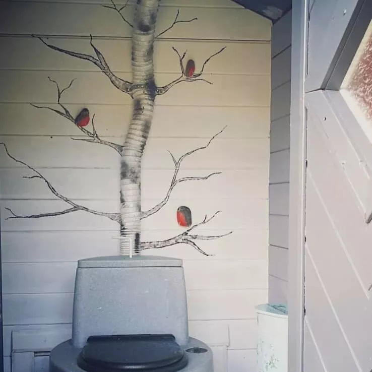 huussi, jossa wc-pöntön putki on maalattu koivuksi