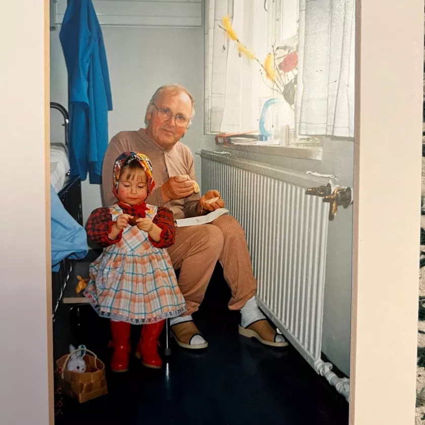 Kehystetty valokuva, jossa noidaksi pukeutunut kaksivuotias Lotta virpoo sairaalassa olevalle papalle.
