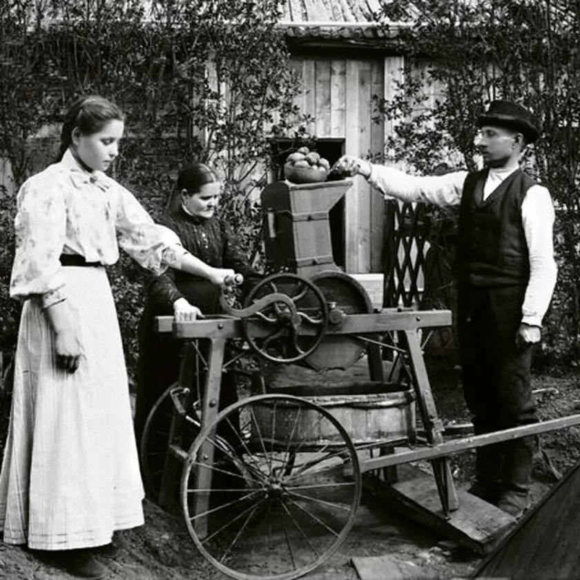 Nainen ja mies käyttävät perunajauhomyllyä vuonna 1910