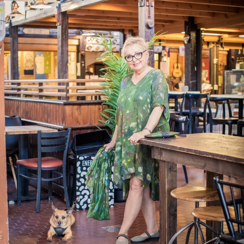 Kirjailija Raija Oranen seisoo Hietaniemen kauppahallissa koiransa kanssa.