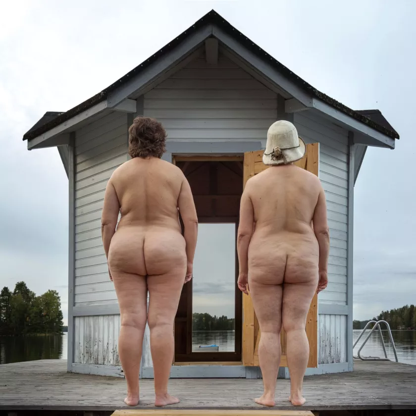 Suuri persenäyttely -valokuvanäyttelyn teos: kaksi ihmistä seisoo alasti selkä kameraan päin laiturilla.