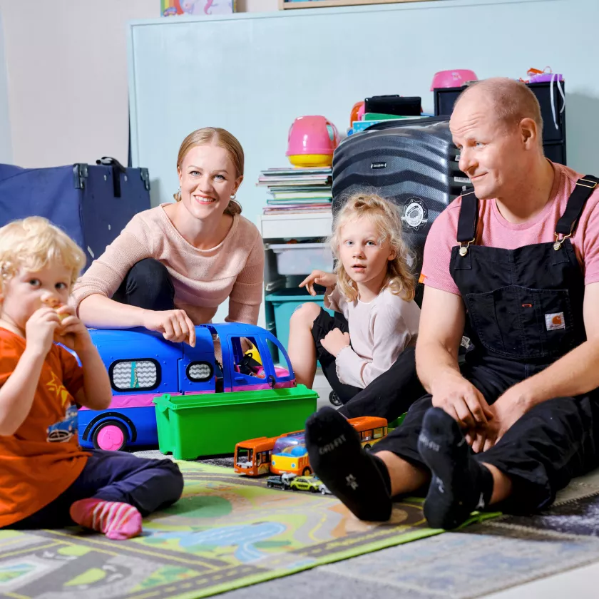 Katerina ja Pasi istuvat lattialla lastensa Hugon ja Aadan kanssa. 