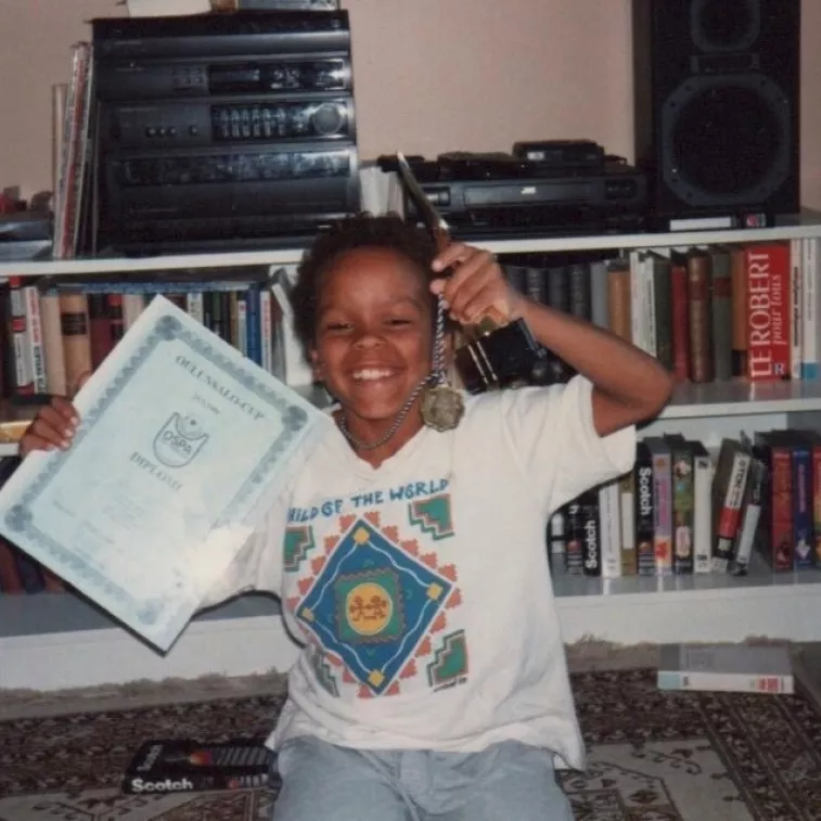 Yhdeksänvuotias Ernest pitelee kädessään diplomia ja mitalia ja hymyilee kameralle.