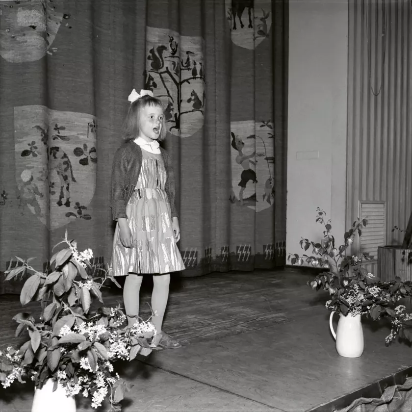 Nuori tyttö lausuu runoa näyttämöllä. Lausuntasitys kansakoulun kulttuurikilpailuista Imatralla vuonna 1957. 