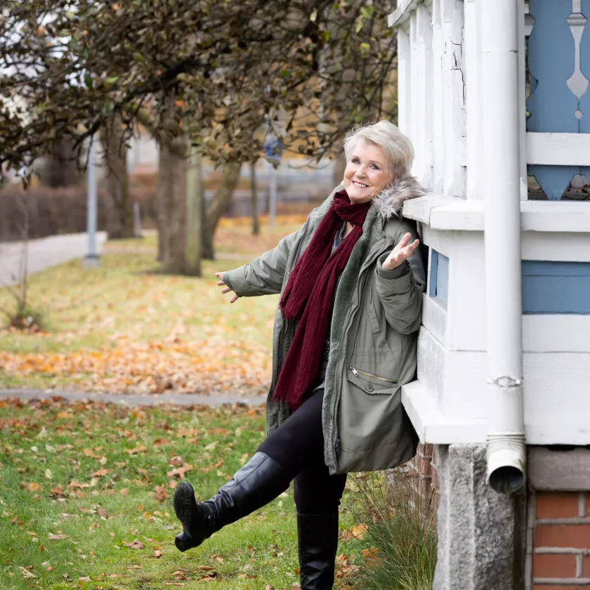 Lea Laven nostaa jalkaa ilmaan nojatessaan vanhan talon seinään.