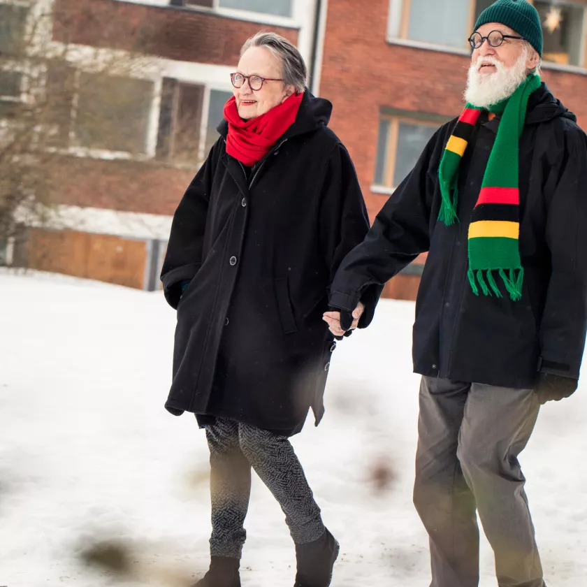 Leila ja Esa Peltonen kävelevät ulkona käsi kädessä kotinsa lähellä Munkkiniemessä, Helsingissä.