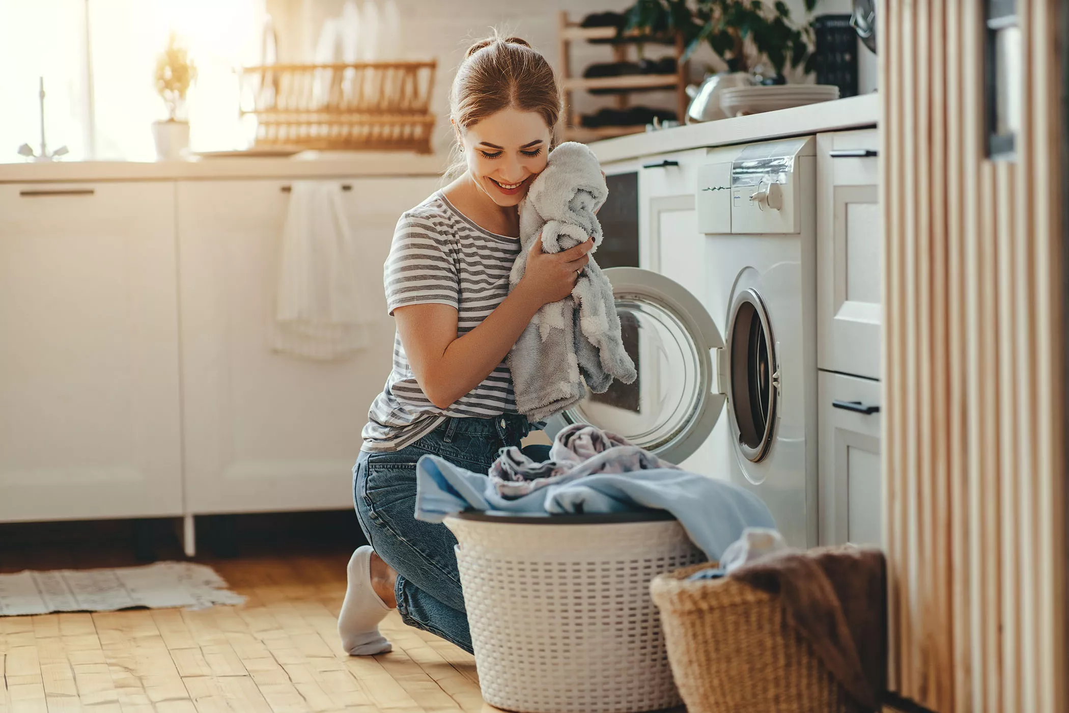 Kuinka paljon pyykkiä koneeseen? Nainen laittaa pyykkiä koneeseen.