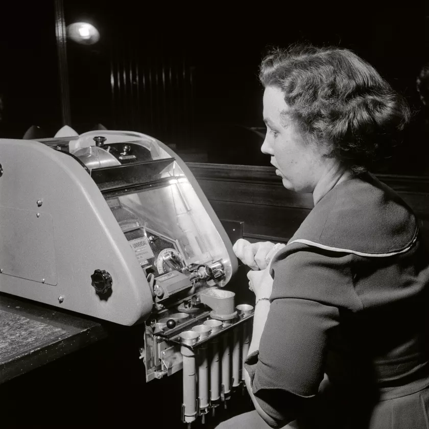 Pankkivirkailija käyttää kolikoiden laskuun tarvittavaa laitetta pankissa vuonna 1958.
