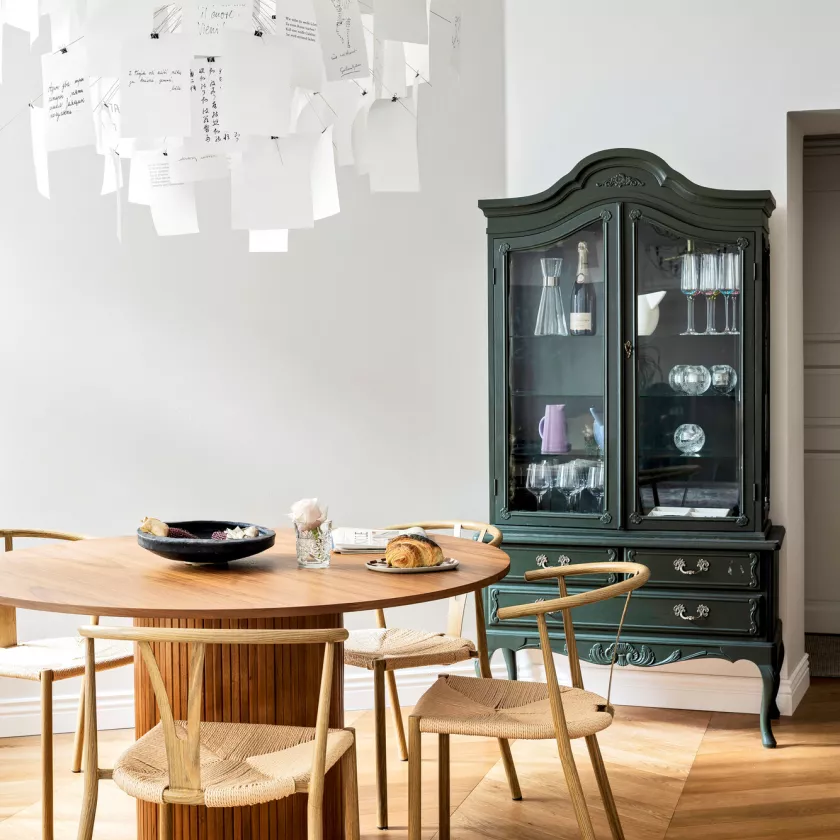 Trendrumilta hankittu pähkinäpuinen Nova-ruokapöytä sointuu keittiön pintojen kanssa tyylikkäästi yhteen. Ruokapöydän tuolit hankittiin Kodin1:stä. Pöydän päälle tunnelmallisen valon antaa Ingo Maurerin Zettel’z 5-valaisin.