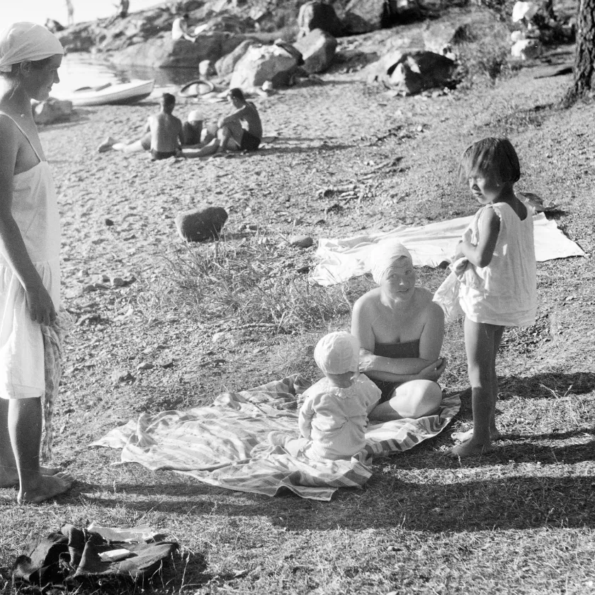 Naiset lapsineen rannalla.