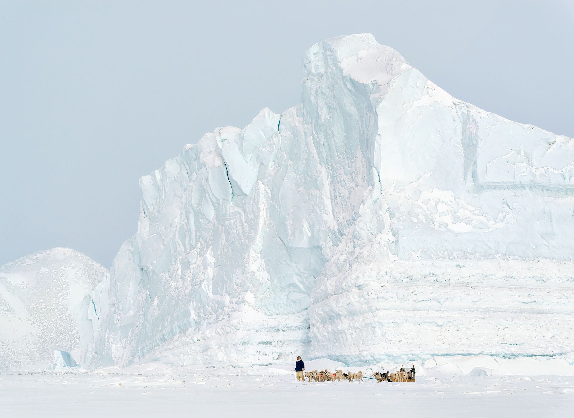 Tässä Tiina Itkosen ottamassa kuvassa metsästäjänuorukainen Piitak katsastaa hylkeenpyyntipaikkoja hyisessä ympäristössä, jossa jäätikkö puskee mereen kerrostalon kokoisia jäävuoria. Meressä ne juuttuvat matalikkoon, kunnes jonon paine työntää reunimmaisen irti. Sitten jäävuoret lipuvat hitaasti ­kohti pohjoista, ohittavat tämän jäävuoren lailla Qaanaaqin ja kääntyvät lopulta takaisin etelään, aina niin alas, että yksi niistä saattoi aikoinaan upottaa Titanicin. 
