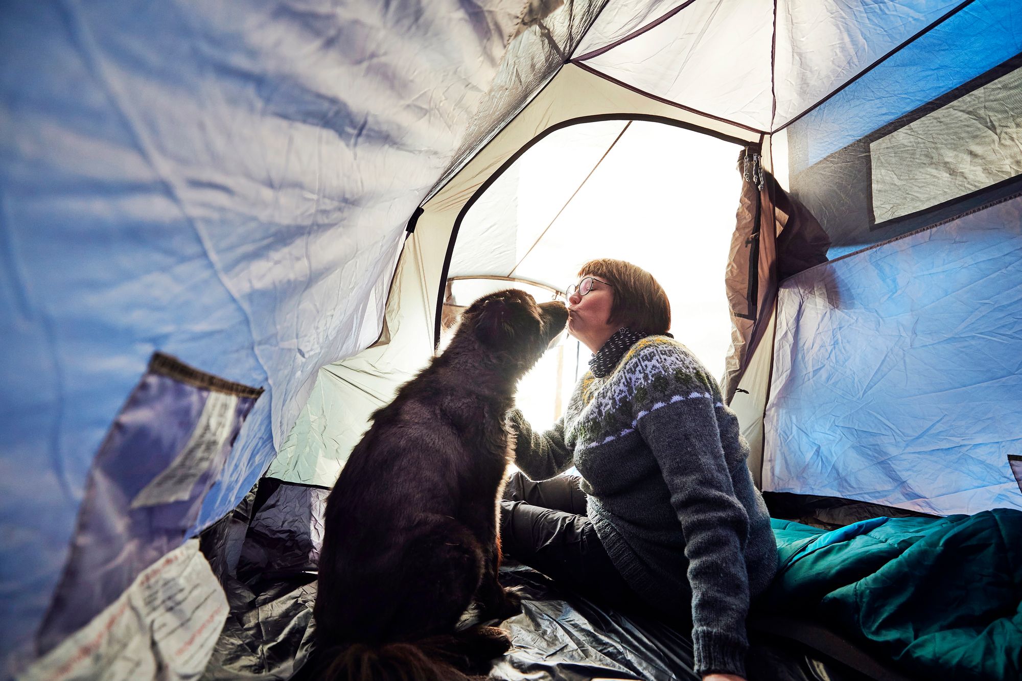 Koira antaa emännälleen pusun teltassa.