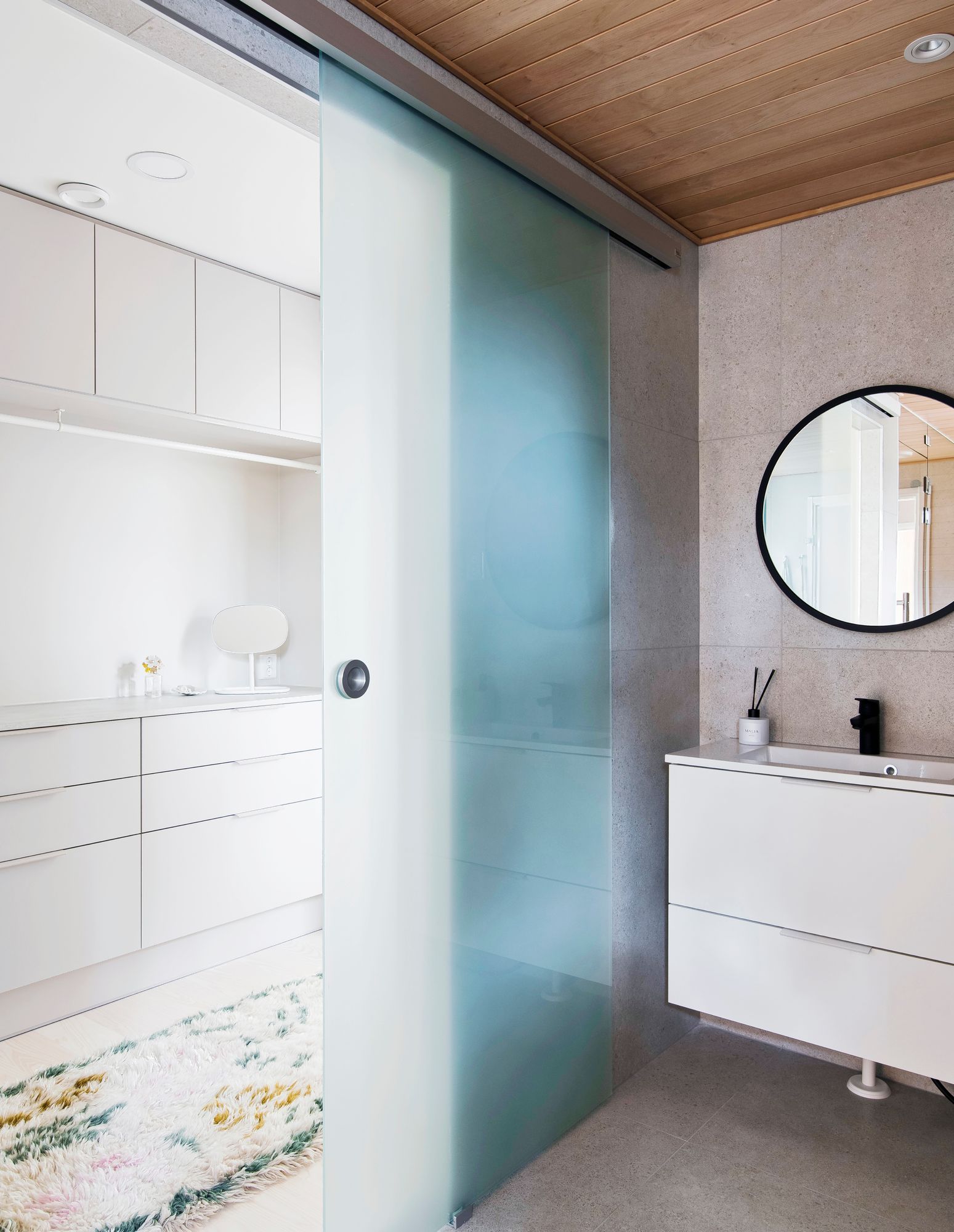 Kastelli Kultarannan kylpyhuoneen ja vaatehuoneen välissä on kosteisiin tiloihin suunniteltu lasiliukuovi, joka päästää valoa kylpyhuoneeseen. Kuva: Niclas Makela