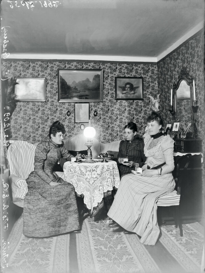 Kolme naista kahvittelevat salissa.