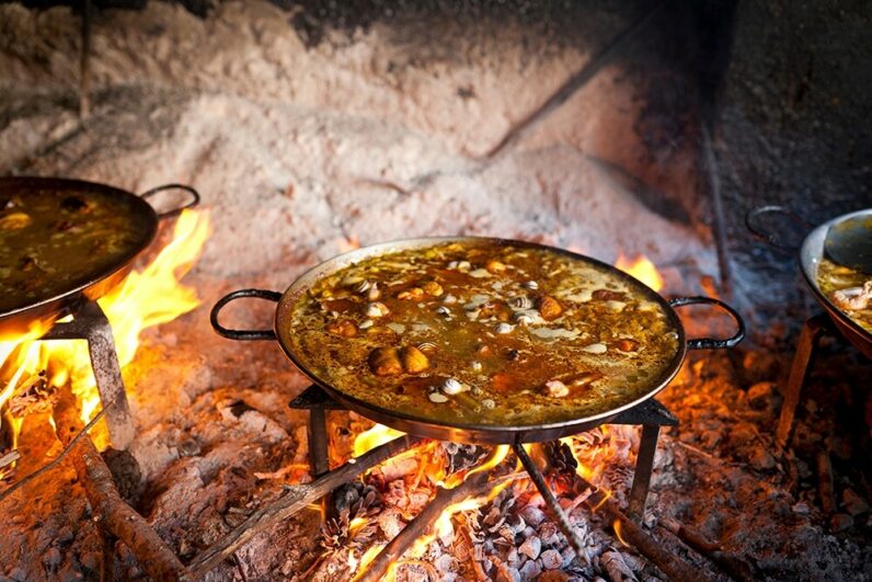 Valencian paella cooking on log fire in local Spainish village