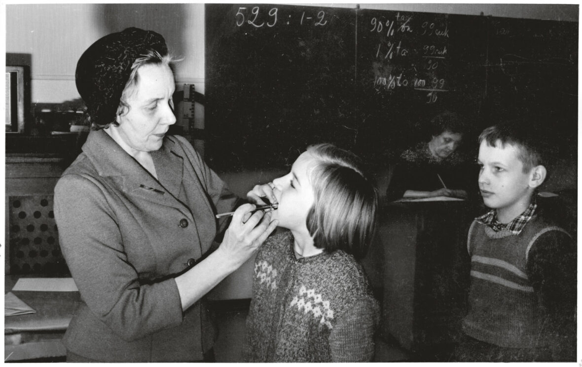 Hammaslääkäri tarkasti lasten hampaita luokassa päivänvalossa vuonna 1961.
